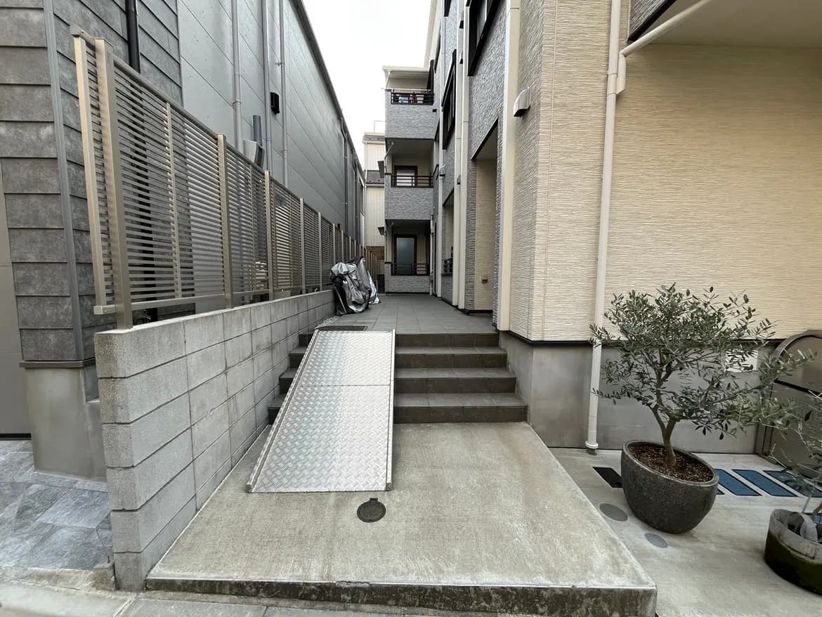現代的な建物のエントランス、植木と車椅子用スロープがあるアプローチ