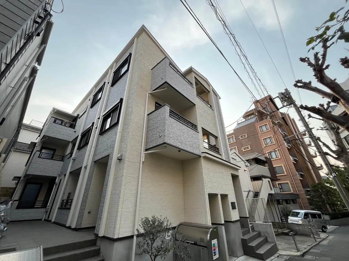 現代的な外観の都市型マンション、清潔感のある明るい外壁、階段付きのエントランス