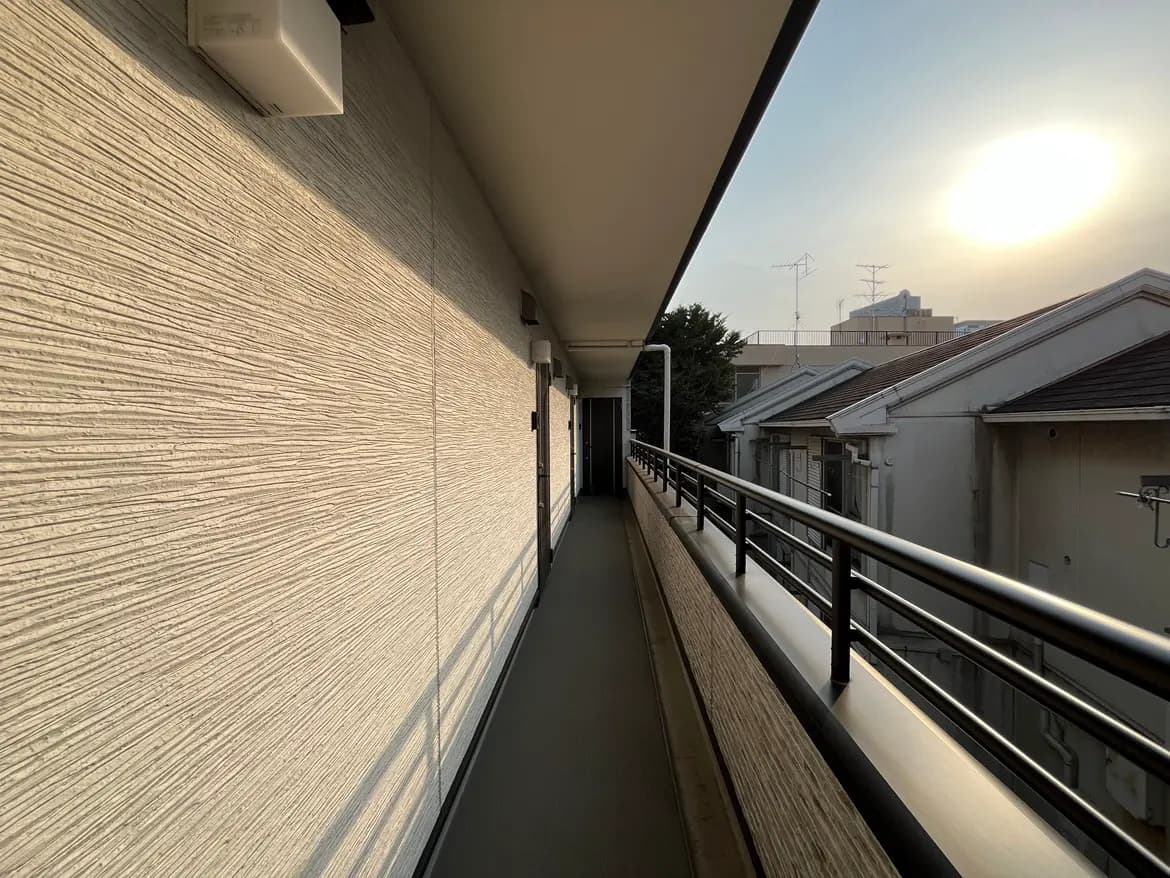 夕方の日差しを浴びるアパートのバルコニー、手すりと壁の影、都市の住宅風景