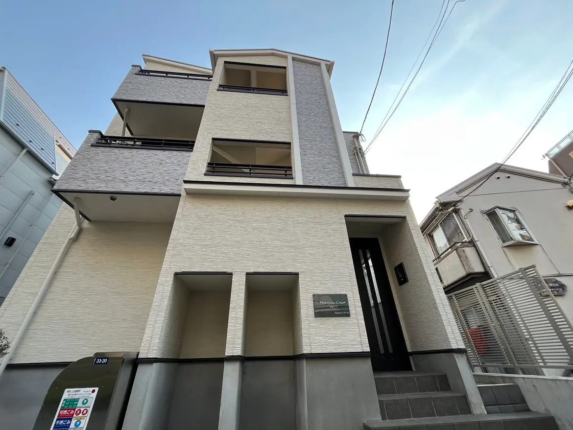 都市の住宅街にあるモダンな建築スタイルのアパートメント外観、明るいファサード、階段と入り口