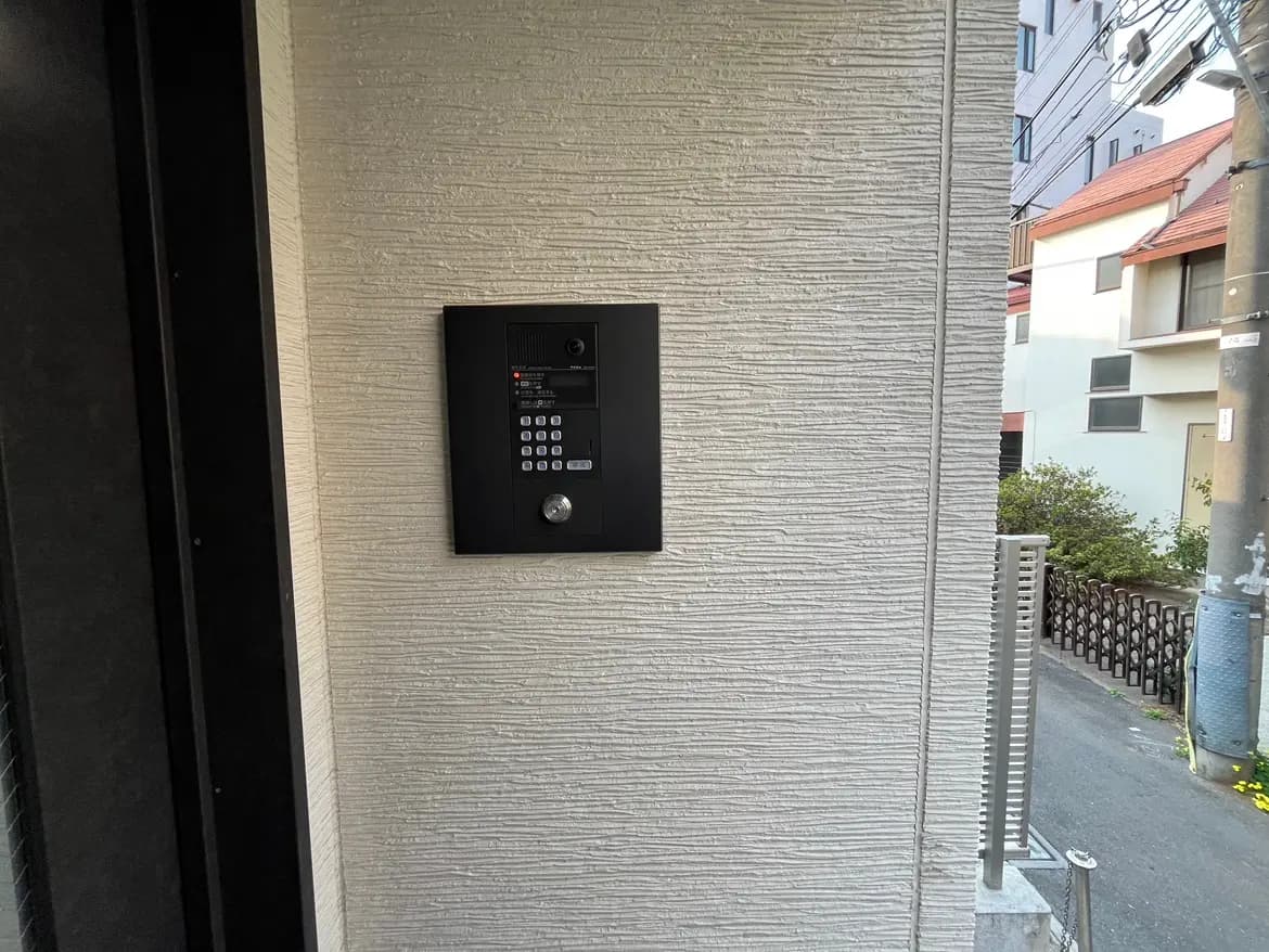 建物のエントランスに設置されたインターホンシステム、セキュリティ用キーパッドとカメラ付き、都市環境の背景
