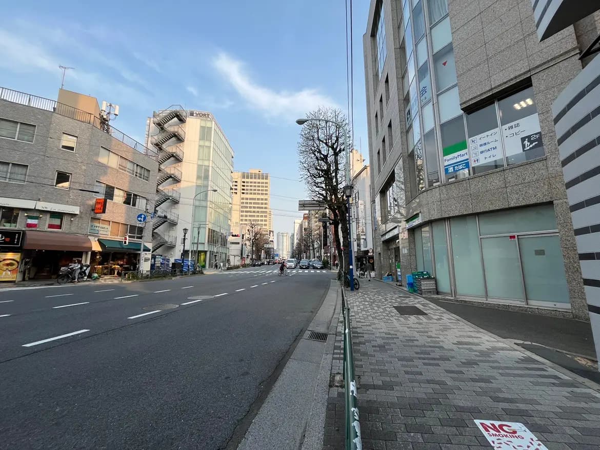 日本の都市の街並み、ビルと商店が並ぶ道路、明るい日差しの中の風景