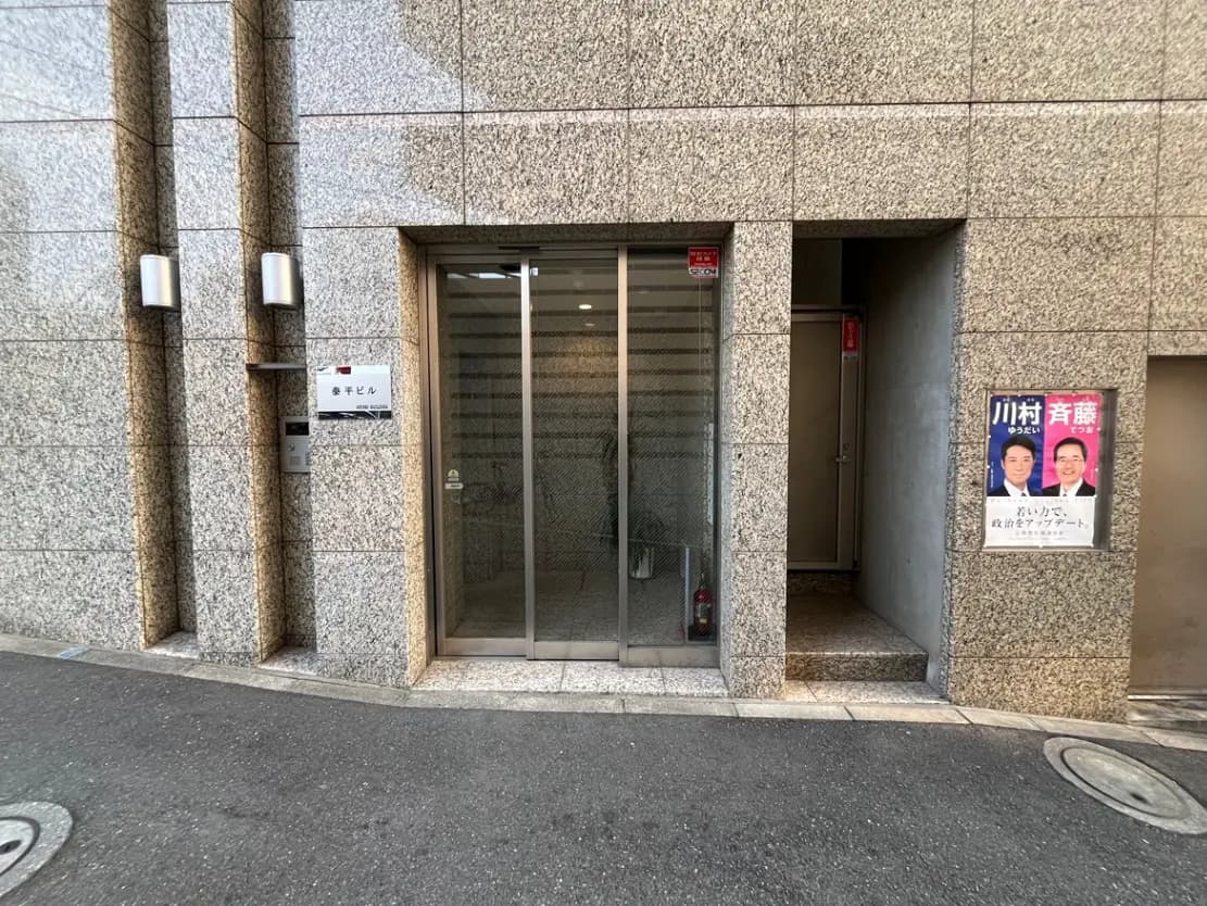 ビルの入り口デザイン、ポスター付きのガラス扉と石造りの外壁