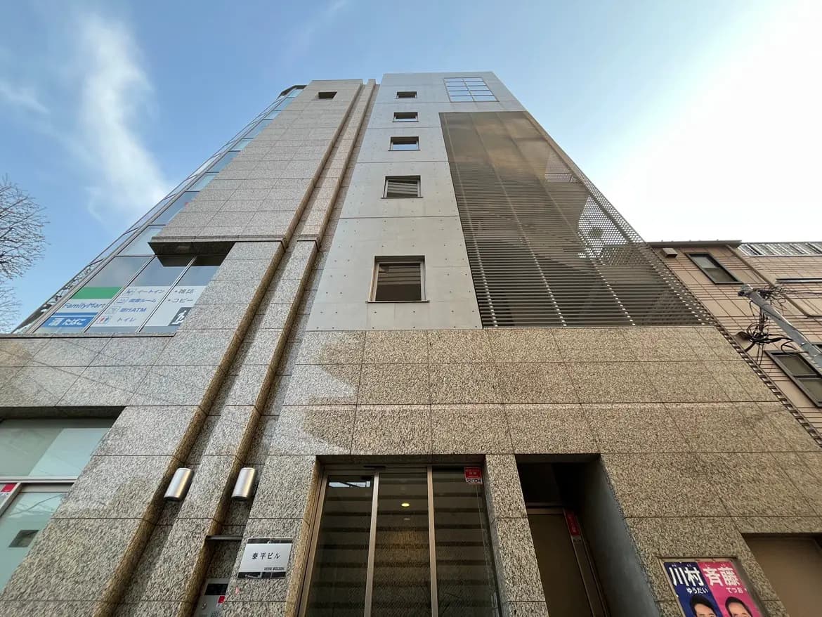 都市型オフィスビル外観、モダンなファサードデザイン、日中のクリアな空とのコントラスト