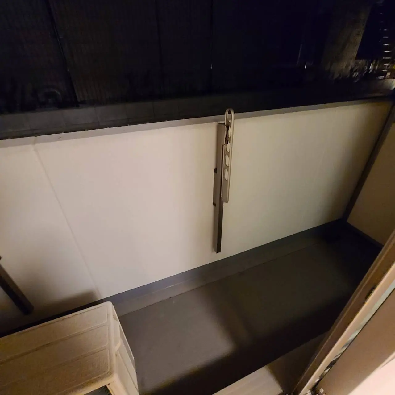 夜間のマンションのバルコニー、手すりに取り付けられた照明、床はグレーのタイル