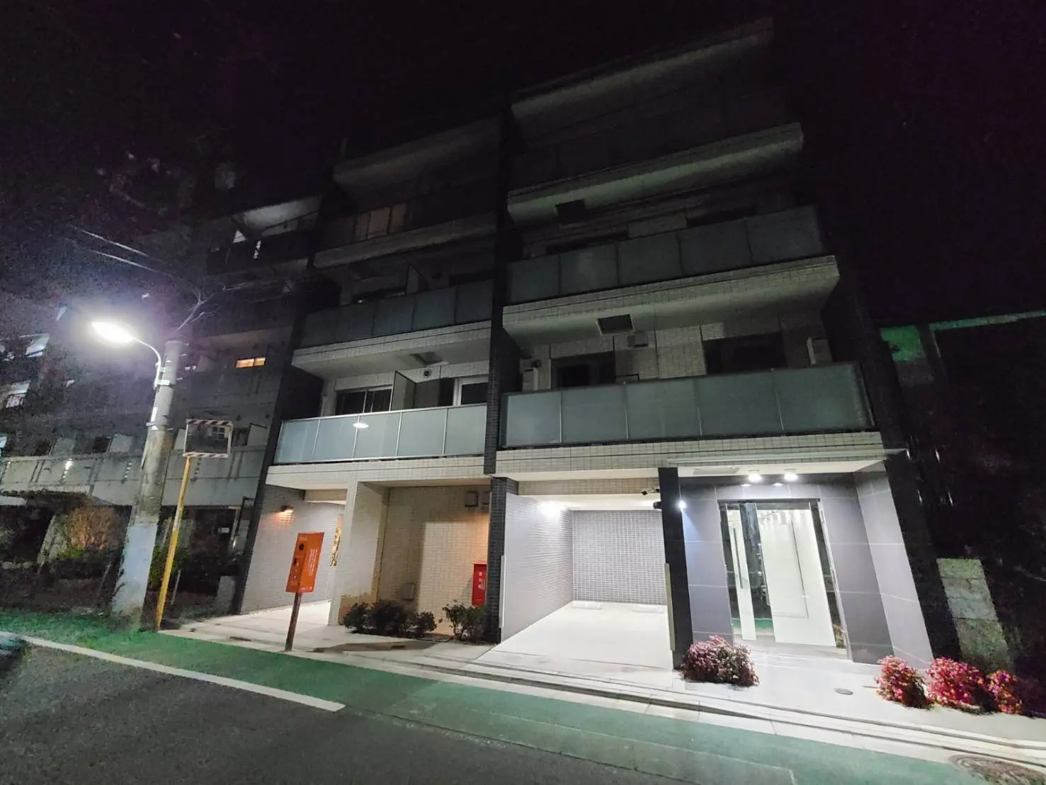 夜景の中のモダンなアパートのエントランス、綺麗にライトアップされた外観