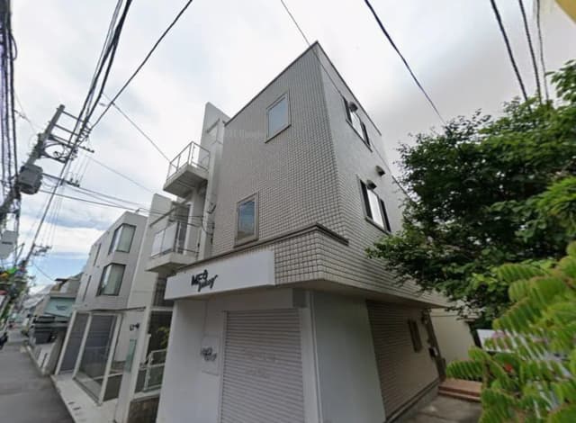 都市部にあるモダンな外観の三階建て住宅、小規模なバルコニーとシャッター付きガレージが特徴