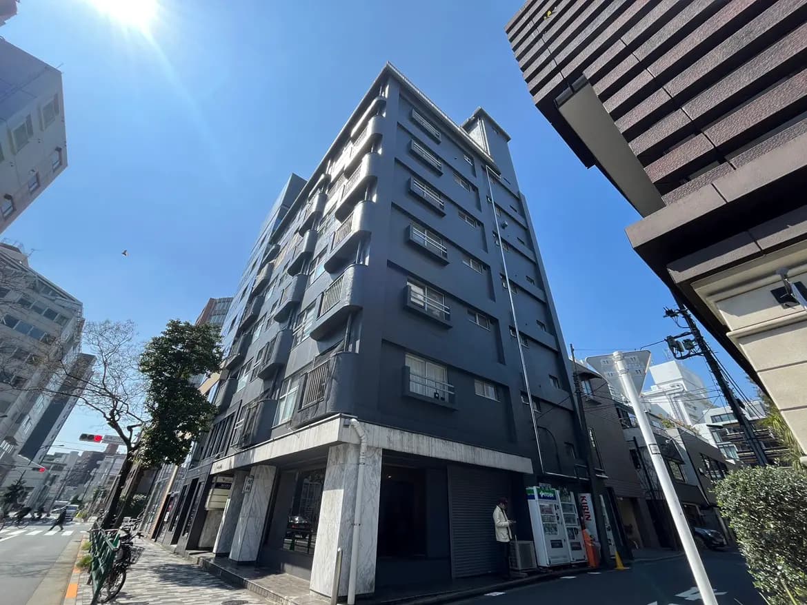都会の中に位置するモダンな外観のオフィスビル、晴れた日の青空と街路樹