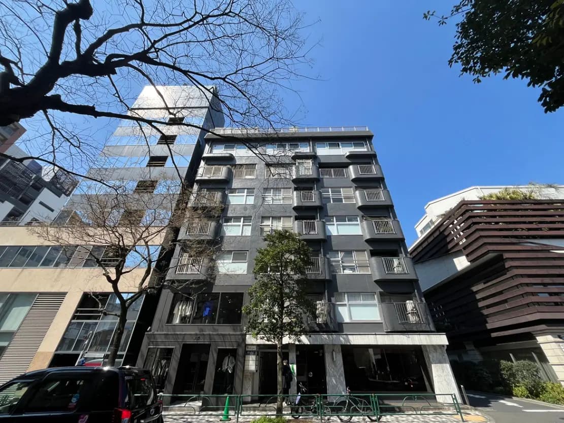 都市のモダンなマンションビル、晴天の下で木々と建築物のファサード