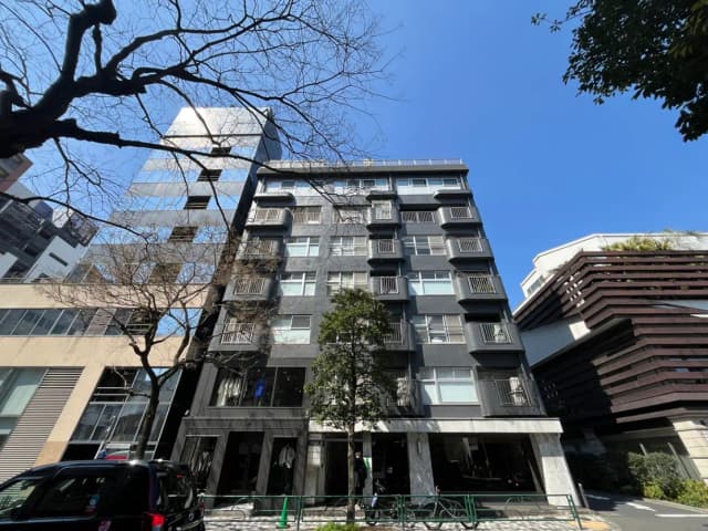 都市のモダンなマンションビル、晴天の下で木々と建築物のファサード