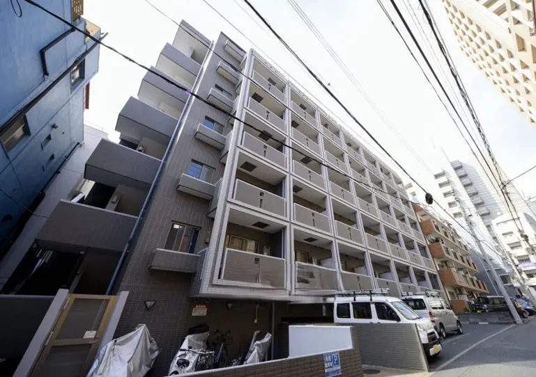 - 現代的な外観のアパートメントビル、バルコニー付きの5階建て、周囲の都市景観と電線が見える画像