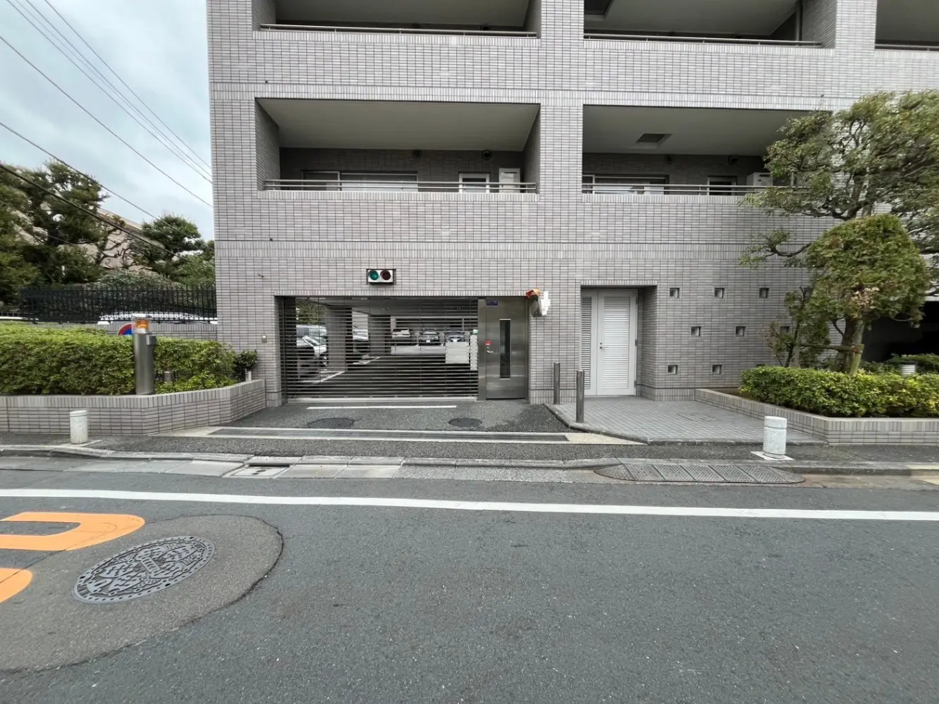 都市のアパート建物のエントランスと外観、歩道と街路樹