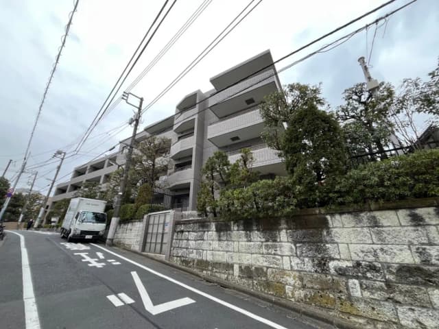 現代的なマンションの外観、石垣と樹木がある歩道、都市の住宅街の通り