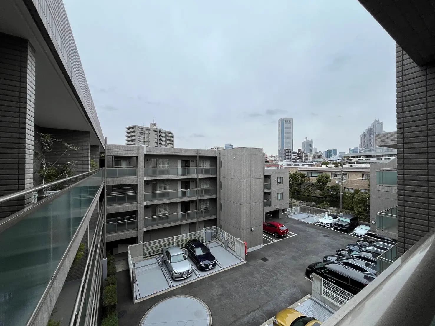 現代的な建物と駐車場を備えた都市の風景、遠くに高層ビルが見える曇天の日