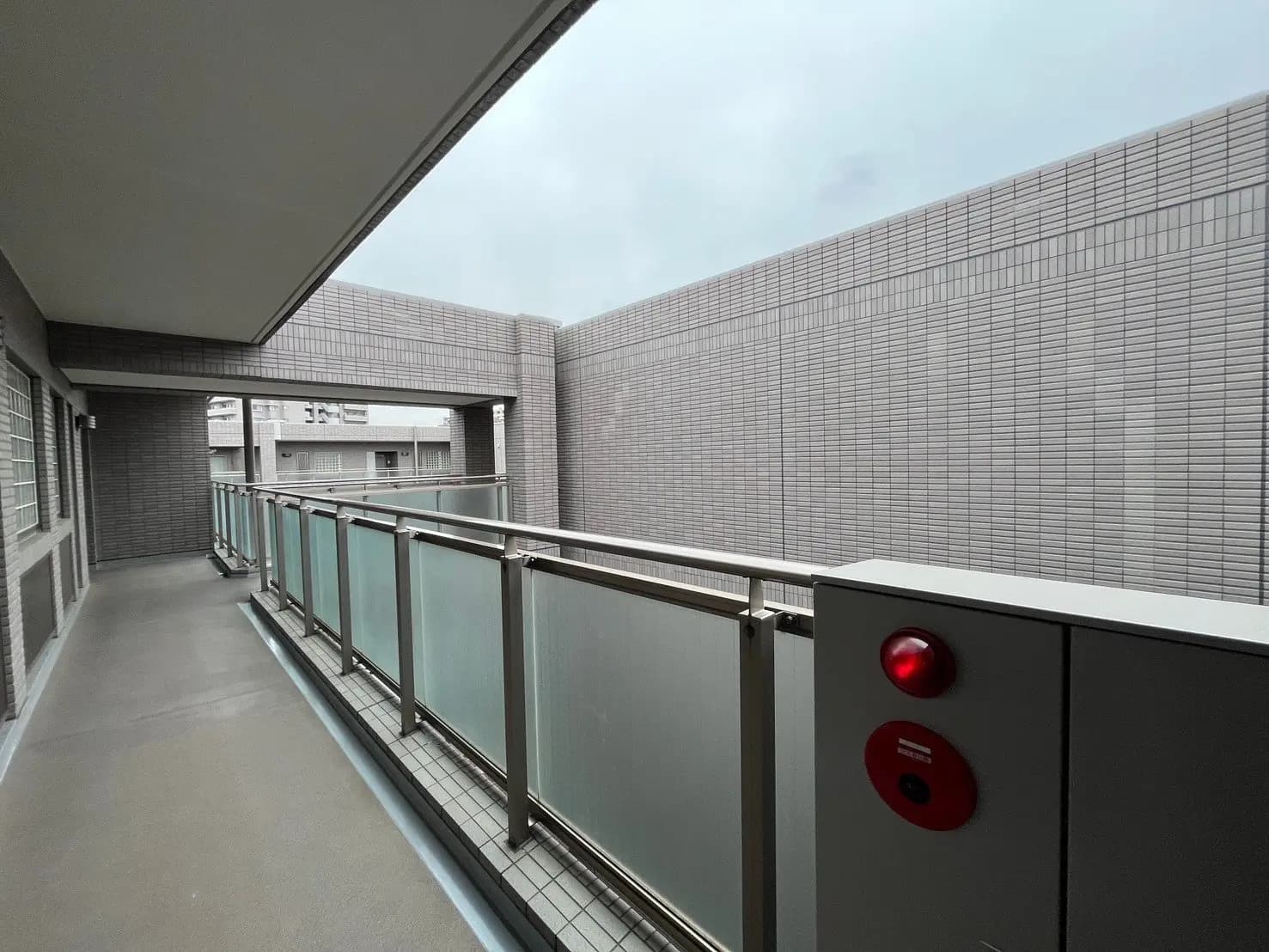 都市のマンションのバルコニー、グレーのタイル張り、ガラスの手すりで覆われた快適な外部空間