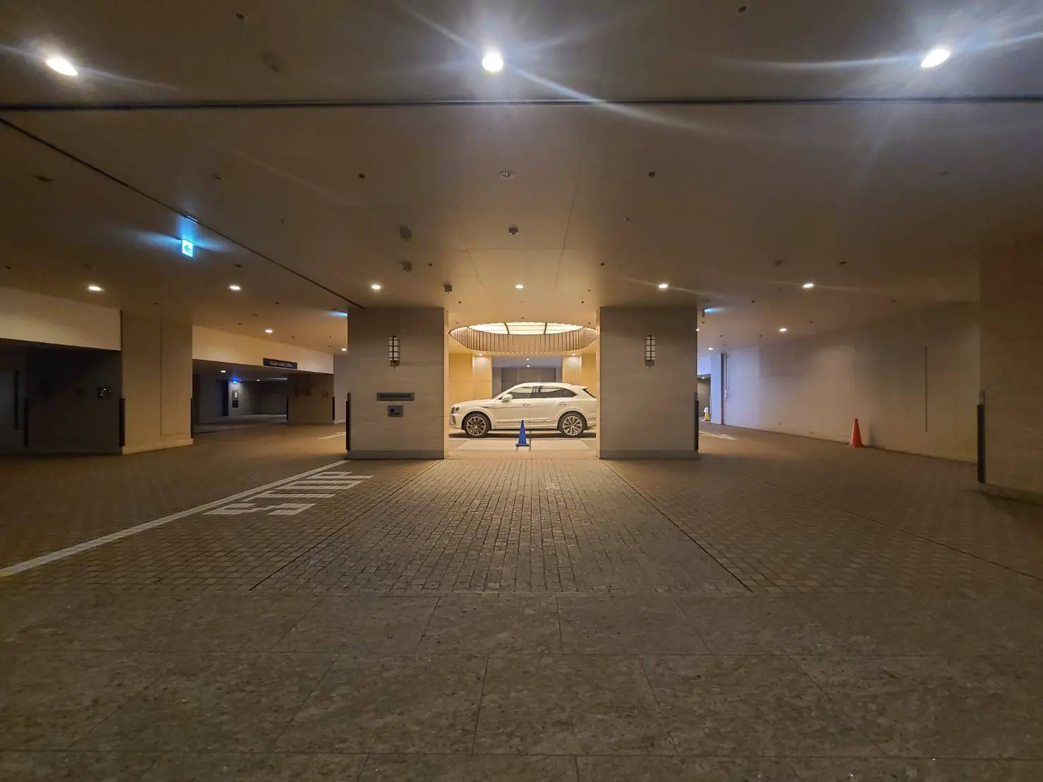 - 高級感のある駐車場のエントランス、天井にはシャンデリアがあり、白い車が停車している風景