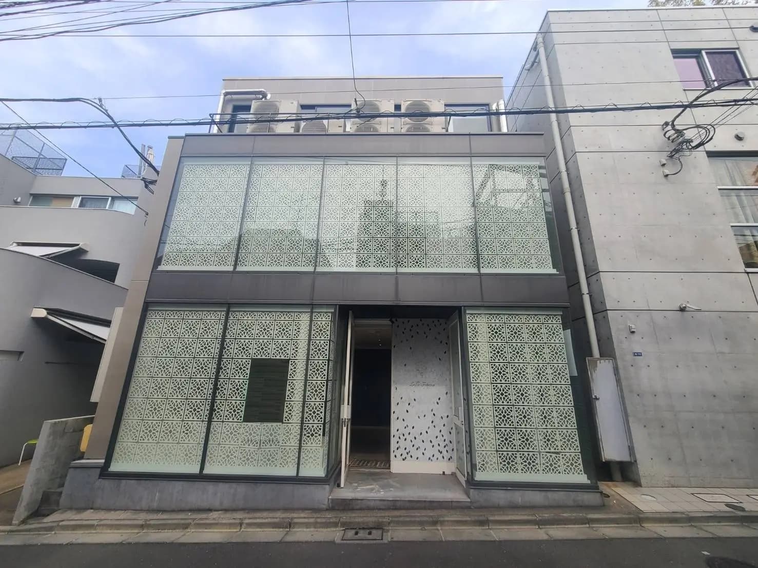 現代的な外観のビルディング、独特なデザインのパターンを施したガラス窓、コンクリートの壁