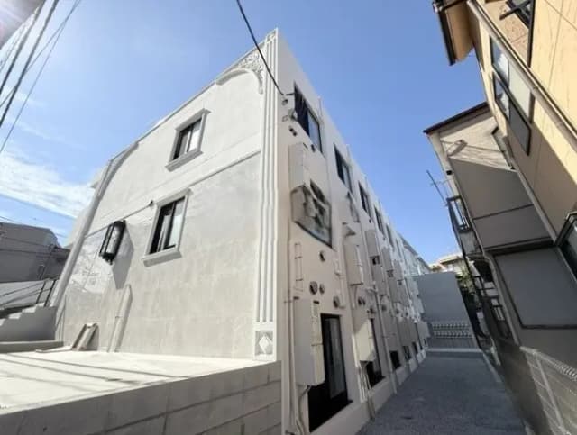 都市部のモダンな灰色の建物外観、晴天の下、細い路地に位置するアパートメント
