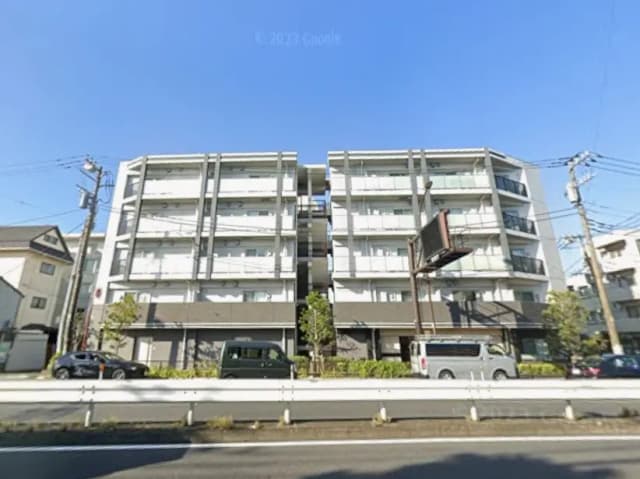 現代的なデザインの都市型マンション、青空のもとでの外観、通りに沿って駐車している車