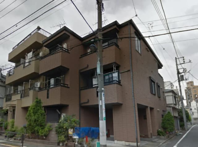 - 褐色の外壁を持つ3階建て住宅、ベランダ付きで周囲には緑が見える都市の風景