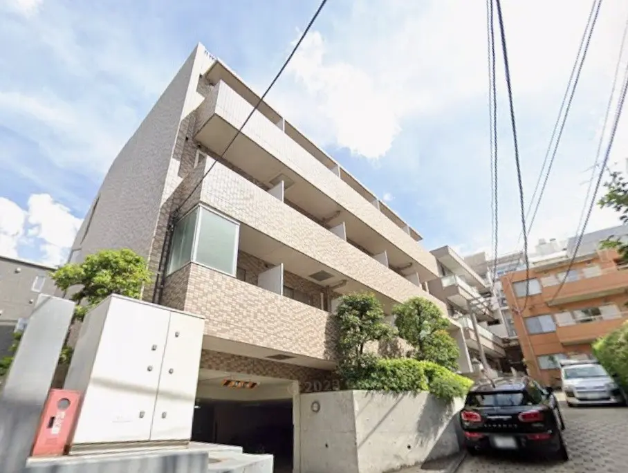 現代的な外観の都市型マンション、明るい日差しと青空、街路樹が彩る住宅街の景色