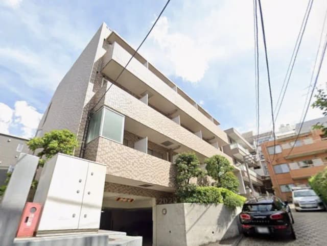 現代的な外観の都市型マンション、明るい日差しと青空、街路樹が彩る住宅街の景色