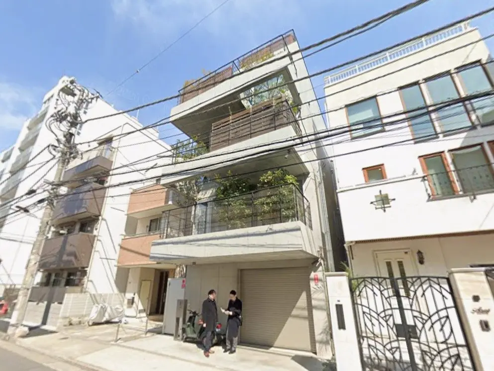 都市部に位置する現代的なマンションと電線、歩道を歩く人々