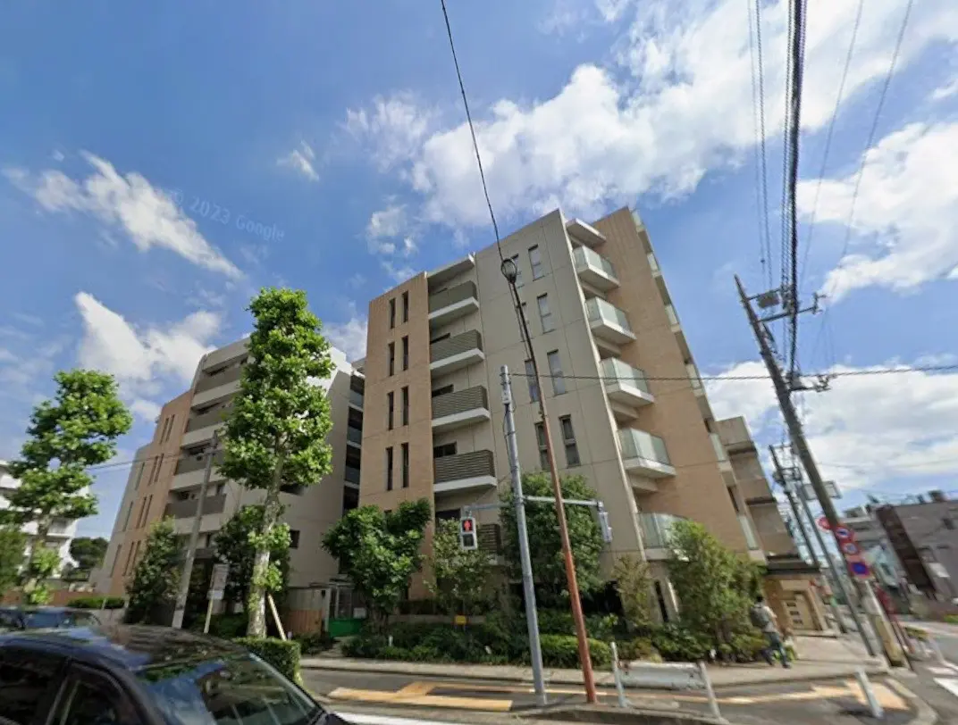 晴れた日の都市風景、複数階建ての現代的なアパート建築、街路樹と電線が見える外観