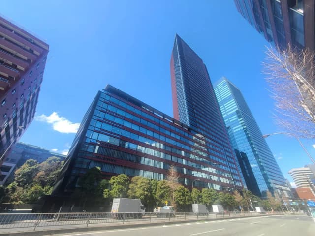 青空の下、現代的な高層ビルとオフィスビルが立ち並ぶ都市の景観