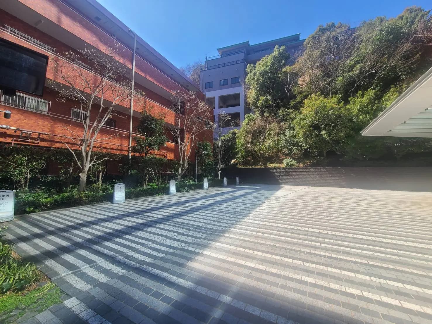 都会的な環境に囲まれたモダンな建築物と整備された歩道、日差しが降り注ぐ快晴の午後
