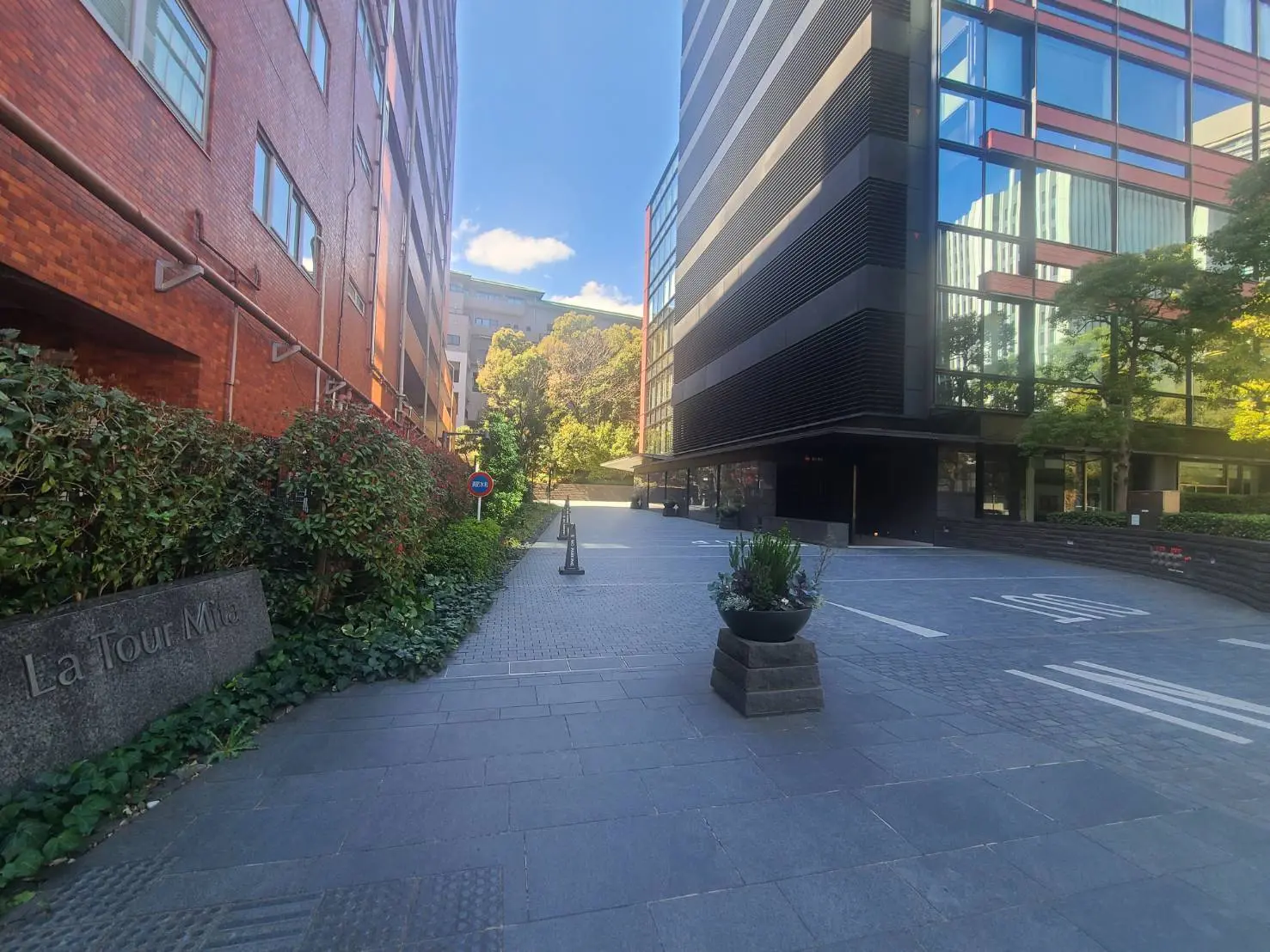 オフィスビルとレンガ造りの建物が並ぶ都市の歩道、晴天の下での明るい風景