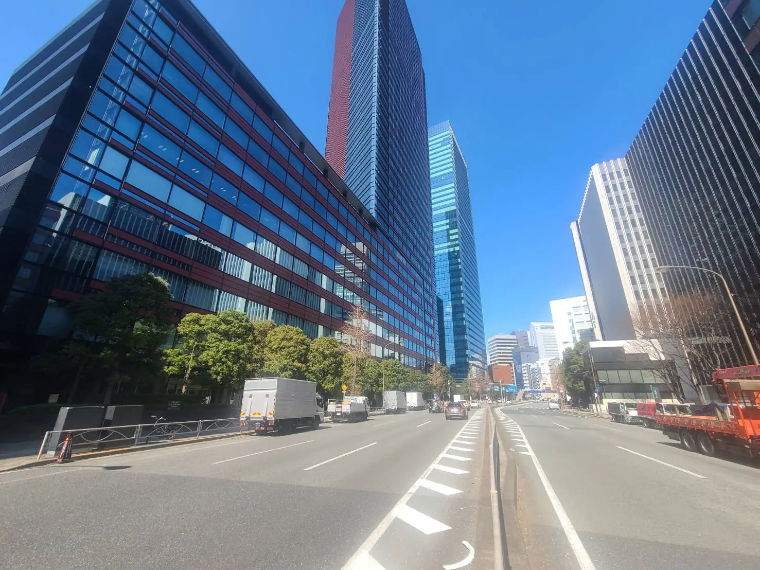 晴れた日の都市風景、道路を挟んで並ぶ高層ビルと、走行する車両
