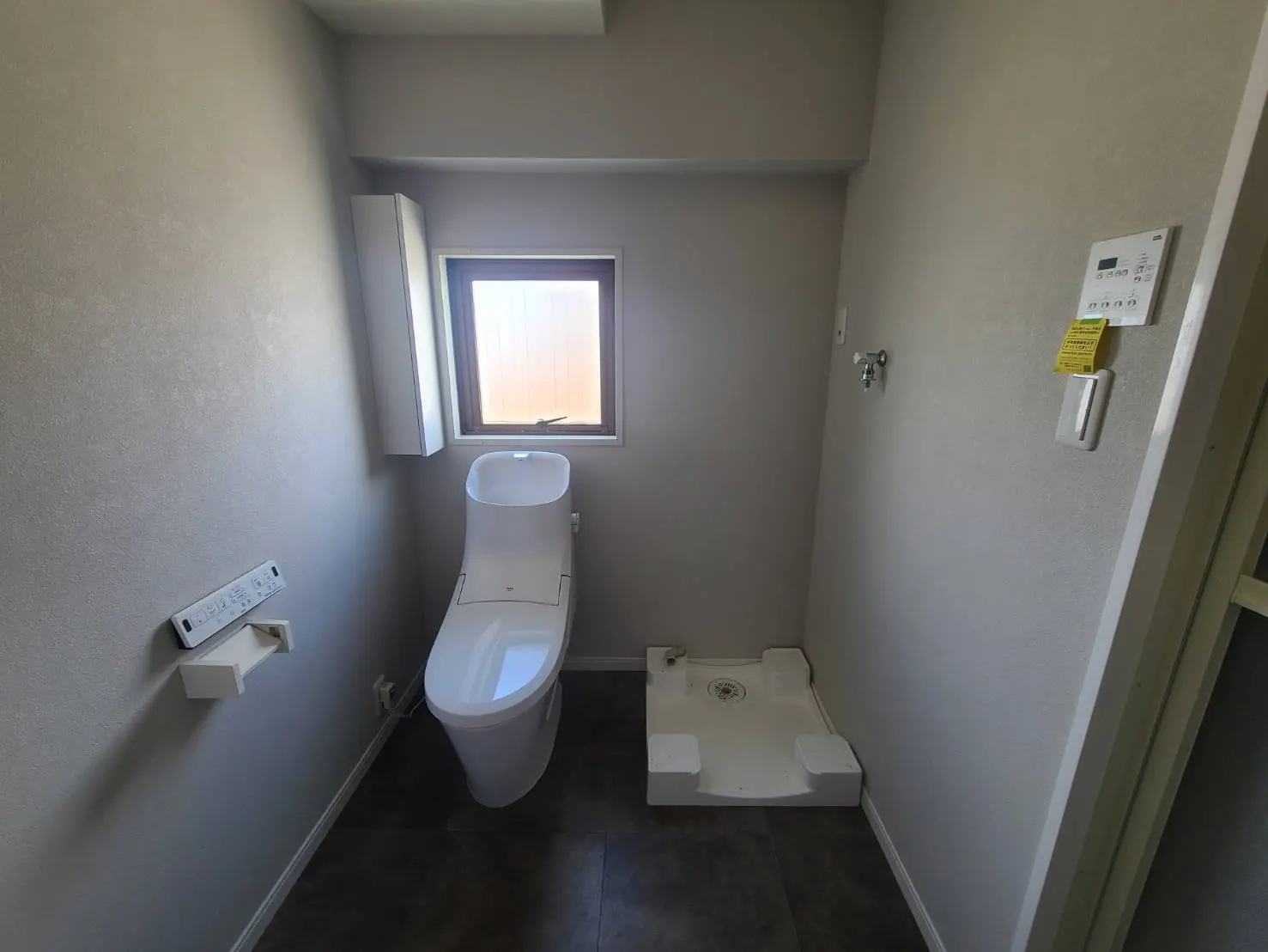 シンプルなデザインのトイレとウォシュレット、小窓から自然光が差し込むバスルーム