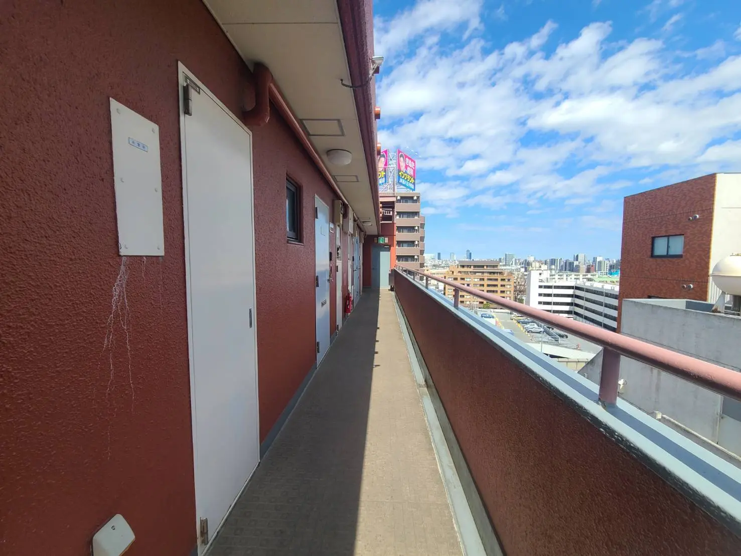 都市のマンションの共用バルコニー、晴れた日の青空と都市の景色