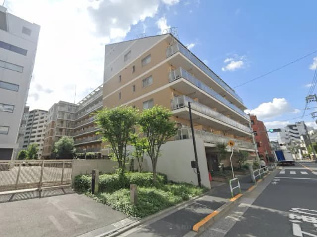 - 街並みに溶け込むモダンなマンション、緑豊かな植栽と明るい外観が特徴の低層住宅の風景