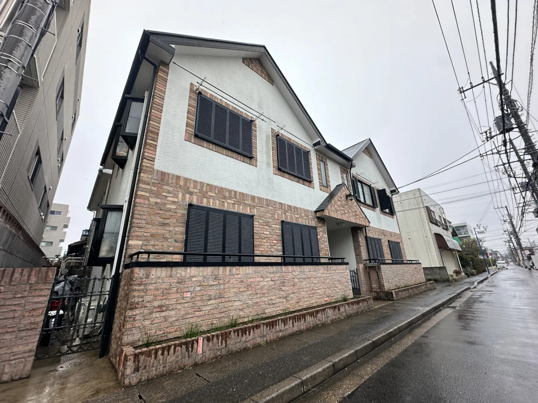 レンガ調の外壁が特徴的なモダンな住宅、雨の日の住宅街の風景