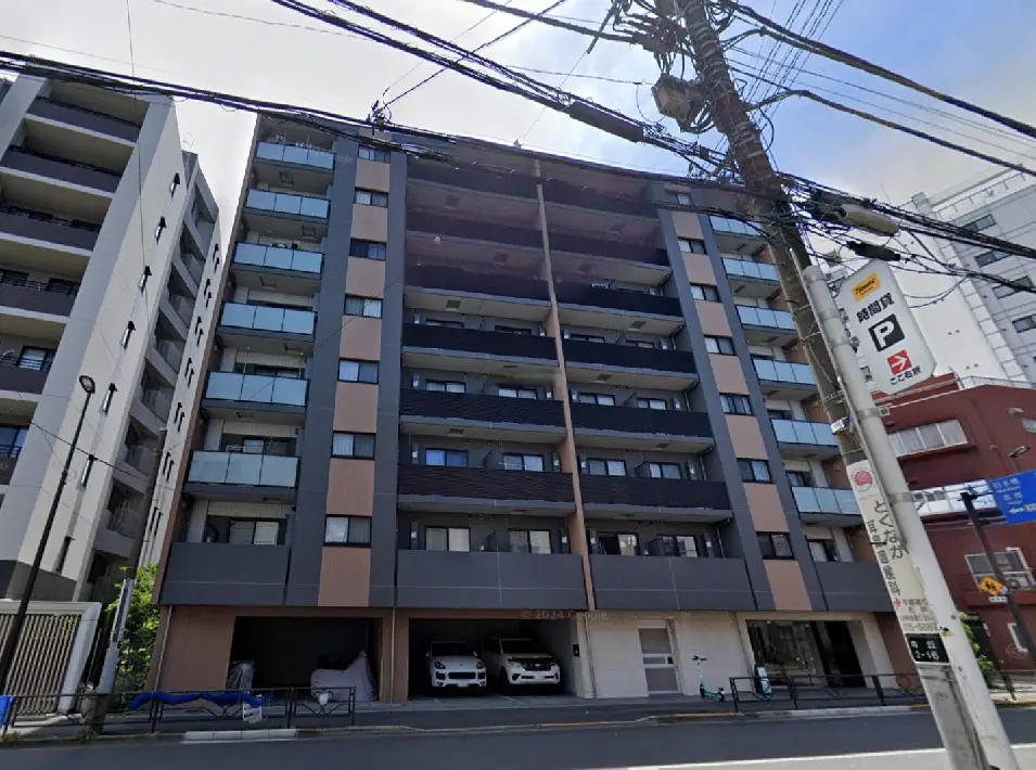 - 現代的なデザインのマンション外観、バルコニー付きの明るいファサード、近くの電柱と道路看板が写っている画像