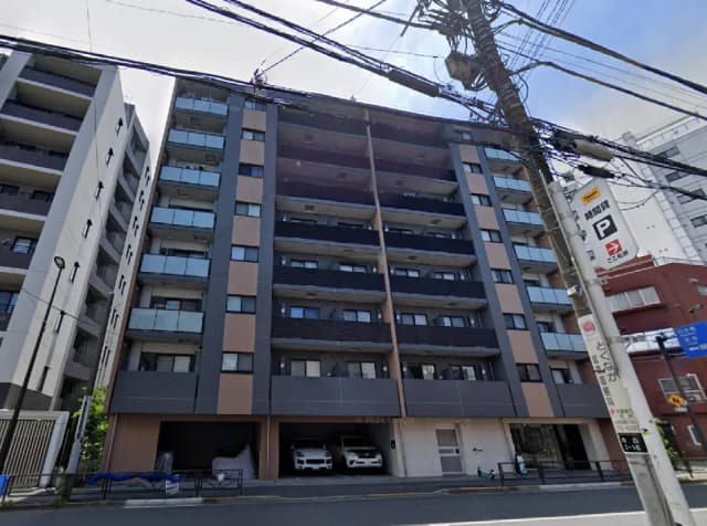 - 現代的なデザインのマンション外観、バルコニー付きの明るいファサード、近くの電柱と道路看板が写っている画像