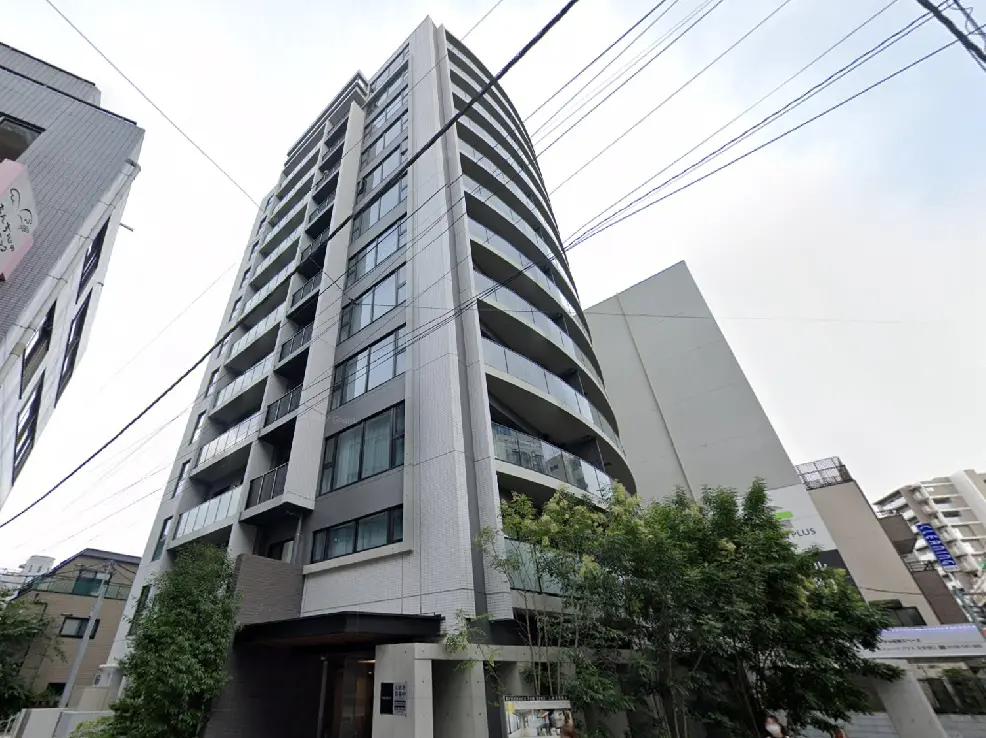 - 現代的なデザインの高層マンション、ガラスバルコニーと緑豊かな入り口が特徴の建物の外観