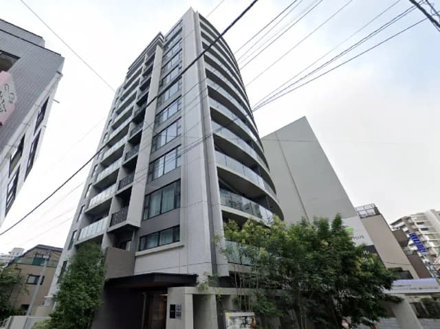 - 現代的なデザインの高層マンション、ガラスバルコニーと緑豊かな入り口が特徴の建物の外観