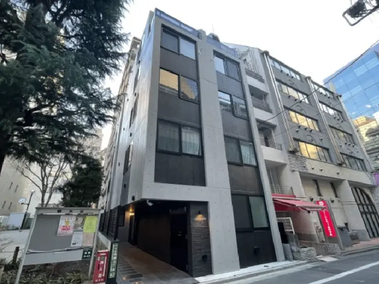 - コンクリートとガラスを使用したモダンな外観のビル、新しいロケーションにある建物、周囲に緑が見える街並み