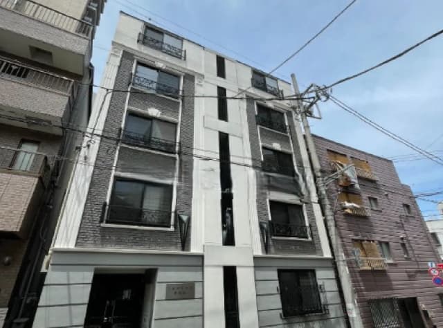 - シンプルでモダンなデザインの住宅ビル、グレーの外壁と大きな窓が特徴、隣接する建物とのコントラストが際立つ外観