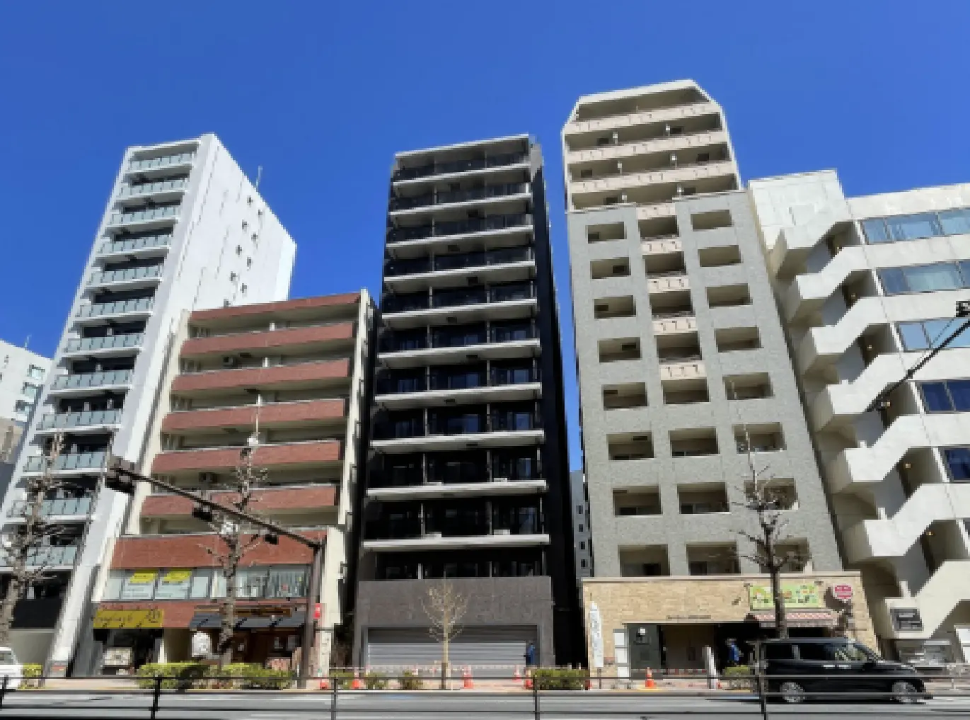 - 近代的な複数棟のマンションが並ぶ街並み、クリアな青空と共に、各建物のデザインが際立つ風景