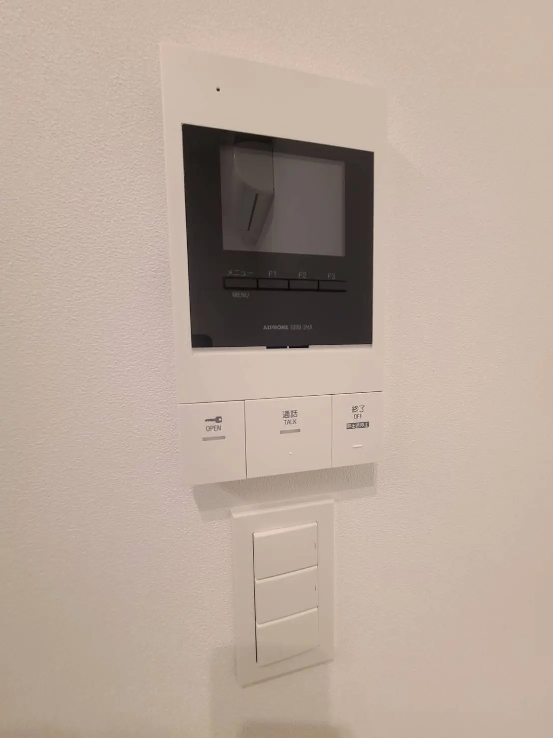 モダンなデザインのインターホンシステム、壁に取り付けられた画面と操作ボタン、スピーカーと通話機能付き