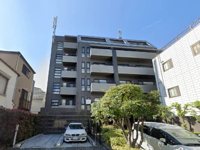 - モダンな外観の5階建てマンション、隣接する住宅と庭に囲まれた駐車スペースがある都市の風景