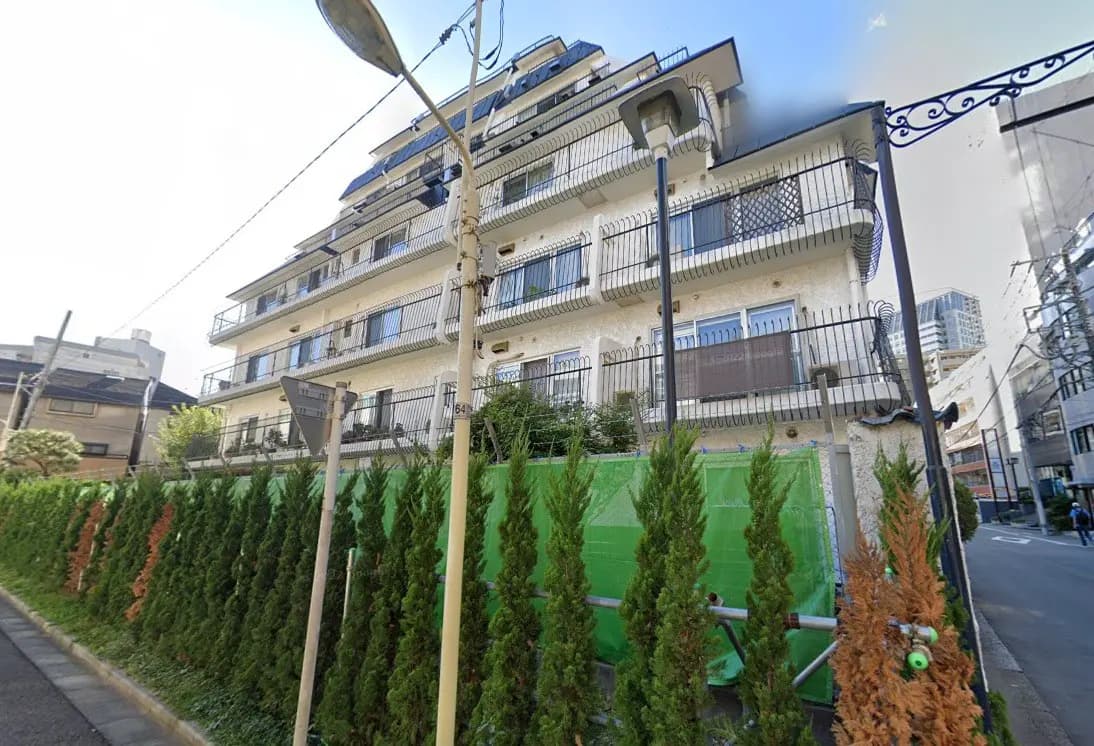 日本の都市部に位置する多階建ての住宅、バルコニーに手すり、緑豊かな植栽が特徴的な風景
