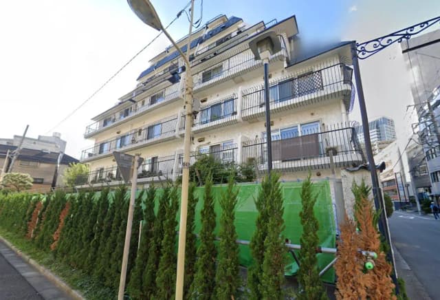 日本の都市部に位置する多階建ての住宅、バルコニーに手すり、緑豊かな植栽が特徴的な風景
