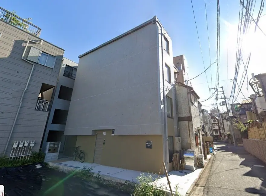 晴れた日の日本の住宅街、グレーの現代的なアパートビル、自転車が置かれた歩道
