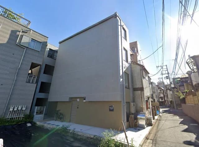 晴れた日の日本の住宅街、グレーの現代的なアパートビル、自転車が置かれた歩道
