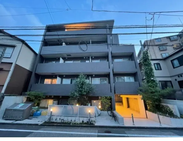都市部に位置するモダンな多階建てのアパート、夕暮れ時の外観、黒とグレーの外壁デザイン